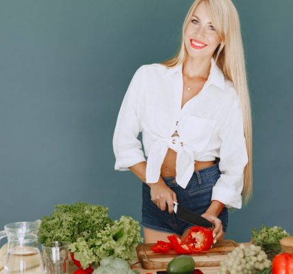 A smiling blonde woman chops vegetables, promoting healthy eating and lifestyle.