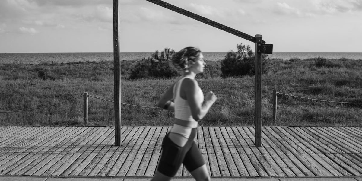 A woman jogs along a coastal boardwalk in Castelldefels, Spain, promoting fitness and outdoor exercise.