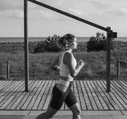 A woman jogs along a coastal boardwalk in Castelldefels, Spain, promoting fitness and outdoor exercise.