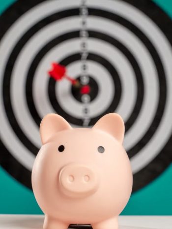 Piggy bank with bullseye dart board symbolizing financial goals and savings.