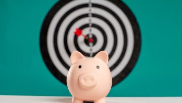 Piggy bank with bullseye dart board symbolizing financial goals and savings.